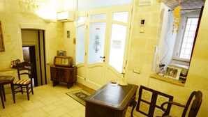 A room with a wooden table, two chairs, a radio, and a door with a frosted glass panel. - B&B Del Castelvecchio (Matera)