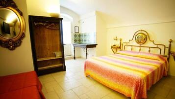 A bedroom with a bed, a wardrobe, a mirror, and a small table.