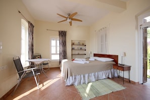A bedroom with a bed, bedside table, chair, and a ceiling fan.