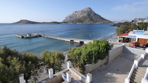 A coastal view with a rocky island, a pier with boats, and a building with a sign.