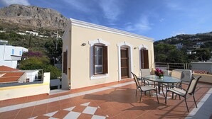 A small building with a tiled patio, a round table, and chairs.