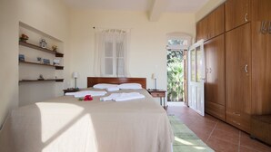 A bedroom with a bed, bedside tables, a wardrobe, a window with curtains, and a view of the outside.