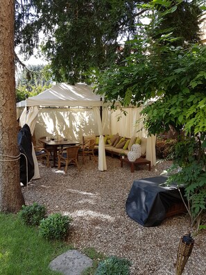 A covered outdoor seating area with a table and chairs, surrounded by trees and a tent. - Dimora Aganoor Relais & Gourmet Experience (Cava de' Tirreni)