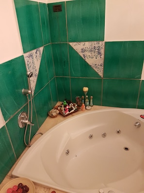 A bathroom with a bathtub, green tiles, a shower, and toiletries on the side. - Dimora Aganoor Relais & Gourmet Experience (Cava de' Tirreni)