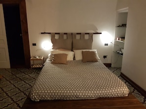 A bedroom with a bed, bedside tables, a nightstand, and a wall-mounted lamp. - Dimora Aganoor Relais & Gourmet Experience (Cava de' Tirreni)