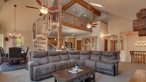 Un salon spacieux avec un grand canapé d’angle, une table basse en bois et un escalier doté d’une rampe en bois.