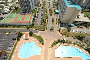 A high-rise building with a rooftop pool and a tennis court.