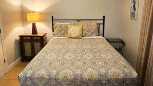A neatly made bed with a patterned bedspread and two pillows, a bedside table with a lamp, and a framed picture on the wall. - AD 1 2104, a spacious 2-bedroom condo in Destin, Fabulous views (Destin)