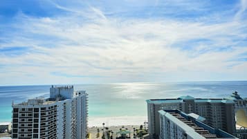A high-rise hotel with a beach view, featuring multiple balconies, a central courtyard, and a parking area.