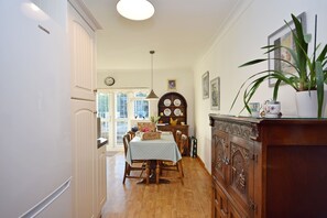 A dining area with a wooden table and chairs, a cabinet with decorative plates, and a potted plant.