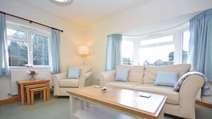A living room with a sofa set, a coffee table, a lamp, and a view through the windows. - Little Crossways , Goodwood -  an annexe that sleeps 2 guests  in 1 bedroom (Chichester)