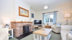 A living room with a brick fireplace, a television, and a sofa. - Little Crossways , Goodwood -  an annexe that sleeps 2 guests  in 1 bedroom (Chichester)