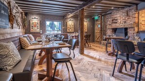 A restaurant with wooden floors, brick walls, and exposed beams. Tables are set with glasses and cutlery.