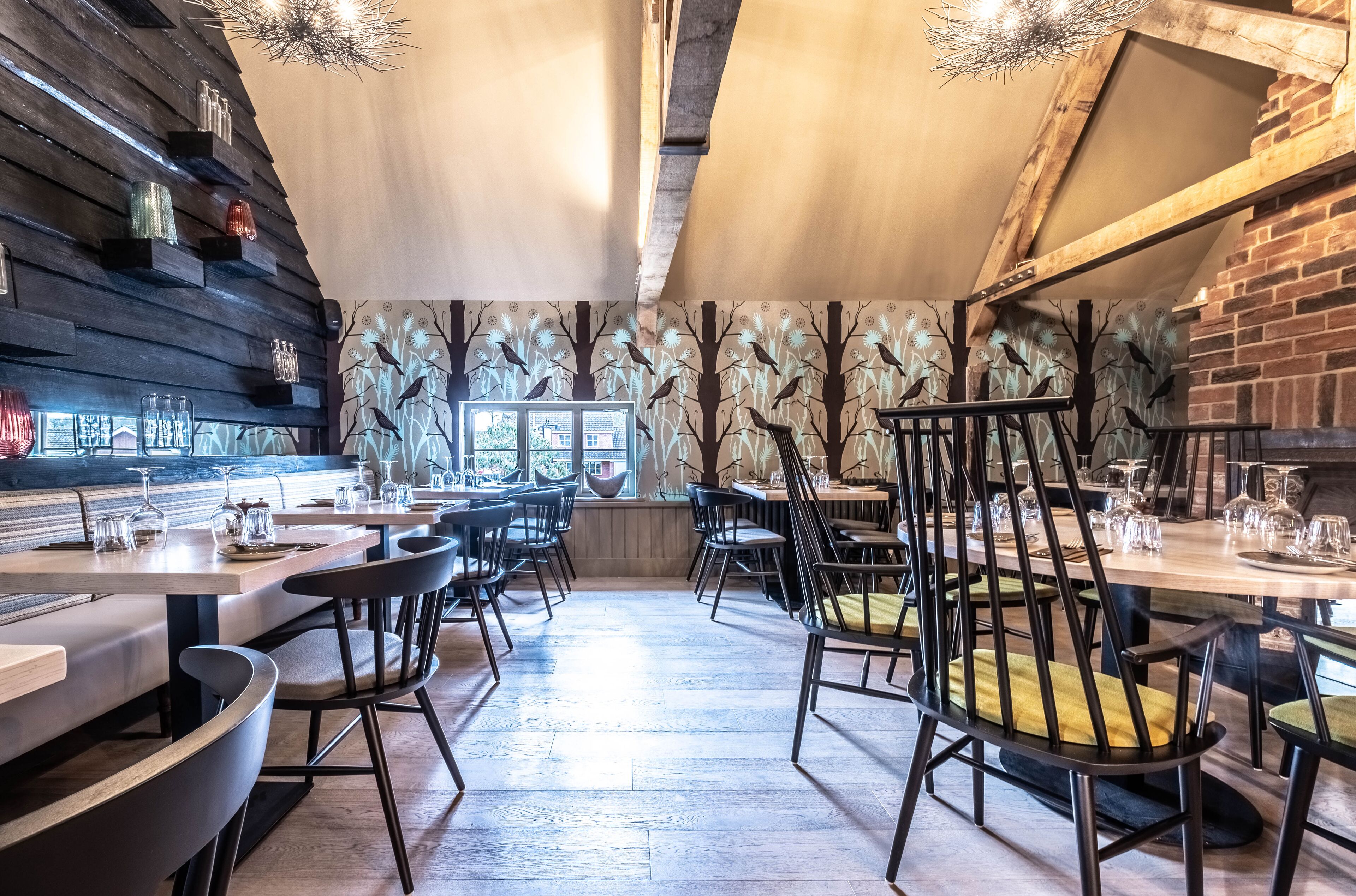 A restaurant with wooden walls, black chairs, and a central table with a yellow cushion.
