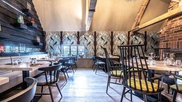 A restaurant with wooden walls, black chairs, and a central table with a yellow cushion.