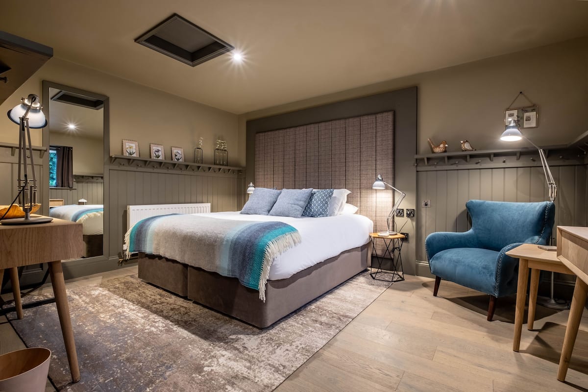 Une chambre à coucher avec un lit, une chaise, un bureau et un miroir.