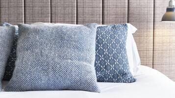 Una cama con tres almohadas, un cabecero y una lámpara de pared.