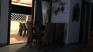 Un coin repas avec des chaises en osier et une table, une porte coulissante donnant sur un espace extérieur, et des décorations murales représentant des poissons.