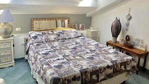 Une chambre à coucher comprenant un lit, des tables de chevet, une lampe et un élément décoratif fixé au mur.