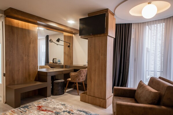 Una sala moderna con una pared de acento de madera, un televisor de pantalla plana montado sobre un pilar de madera, un sofá, una silla y una mesa de centro.