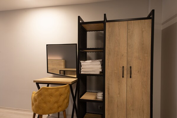 Una habitación con un escritorio de madera, una silla amarilla, un armario con estantes y un espejo.