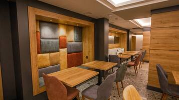 A modern restaurant with wooden tables and cushioned seating.