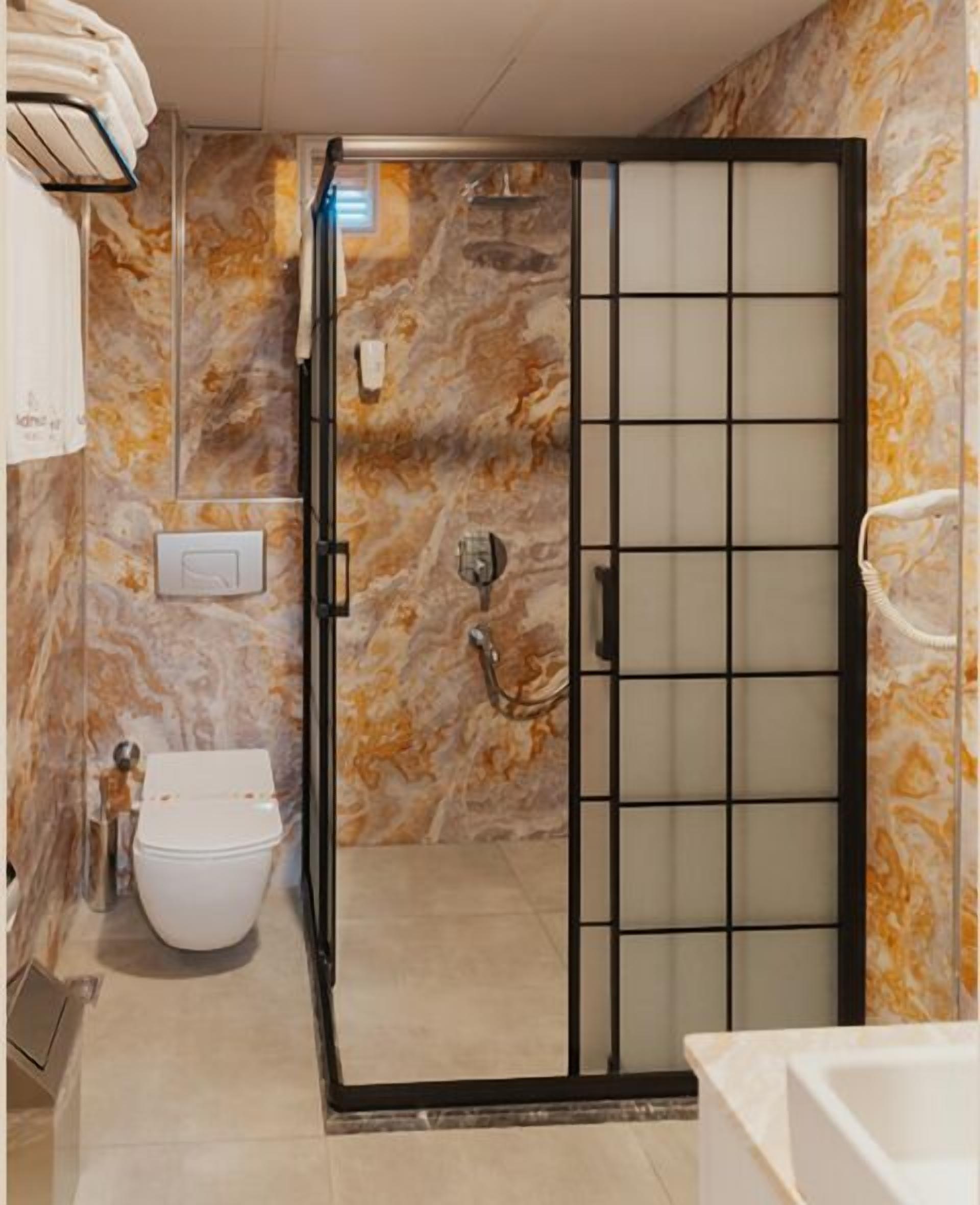 Een badkamer met een douchecabine, toilet en wanden met een marmerlook.