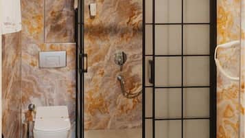 Een badkamer met een douchecabine, toilet en wanden met een marmerlook.