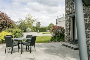 A patio with a table and chairs, surrounded by stone walls and greenery.