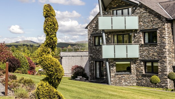 Una casa de piedra de dos plantas con un balcón y un jardín bien cuidado.