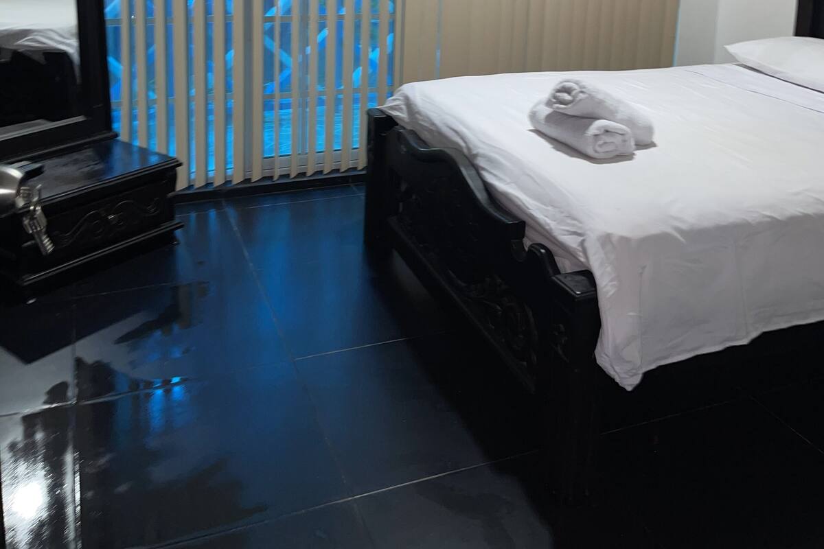 Une chambre d’hôtel avec un lit, une commode et une fenêtre équipée de stores.