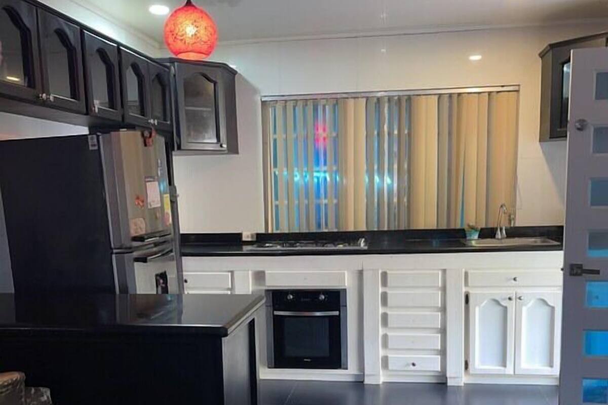 Une cuisine moderne avec un îlot central noir, des armoires blanches et un luminaire suspendu rouge.