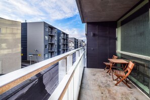Un balcón con vistas a un paisaje urbano, que incluye edificios modernos y un cielo despejado.