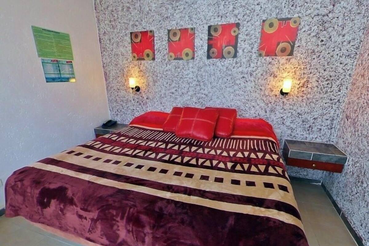 Een slaapkamer met een groot bed, een wandairconditioner en decoratieve muurkunst.