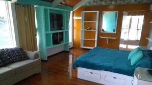Un dormitorio con cama, sofá y estantería empotrada para la televisión.