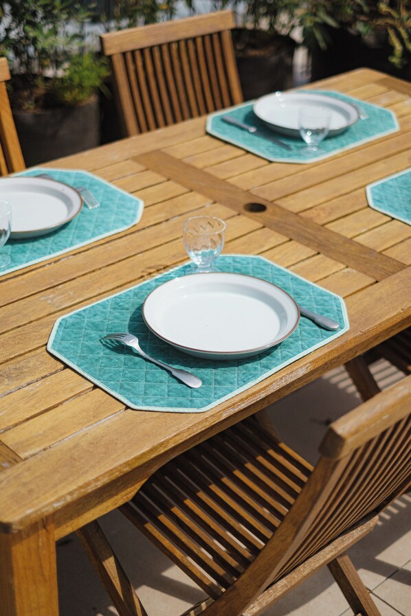 A wooden dining table with four chairs, each with a green placemat. - Rooftop Views of the Arc de Triomphe, by Veeve (Paris)