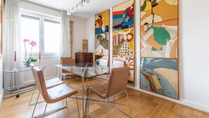A modern dining area with a glass table, leather chairs, and abstract art on the wall. - Rooftop Views of the Arc de Triomphe, by Veeve (Paris)