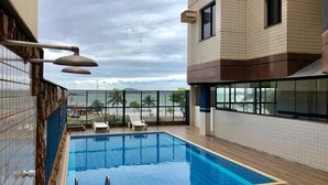 Ein Pool auf dem Dach mit Blick auf den Strand und Palmen.