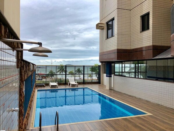 A rooftop swimming pool with a view of the beach and palm trees.