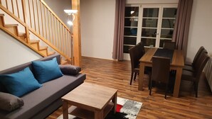 A living room with a sofa, coffee table, and dining table. - Haus Kampl - Apartment Aussee (Pichl-Kainisch)