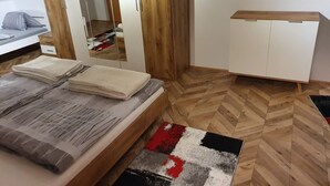 A bedroom with a bed, a wooden wardrobe, a mirror, and a small cabinet. - Haus Kampl - Apartment Aussee (Pichl-Kainisch)