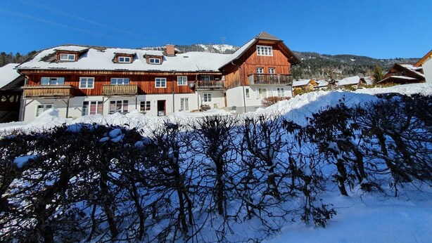 A wooden chalet with multiple balconies, a ski lift in the background, and a snowy mountain landscape. - Haus Kampl - Apartment Aussee (Pichl-Kainisch)