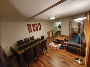 Un espace de vie compact comprenant un coin repas, un canapé, une table basse et une lampe sur pied.