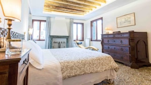 A bedroom with a bed, a dresser, a chair, and a fireplace.