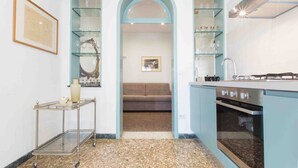A compact kitchen with a built-in oven, a coffee machine, and a small dining area with a sofa.