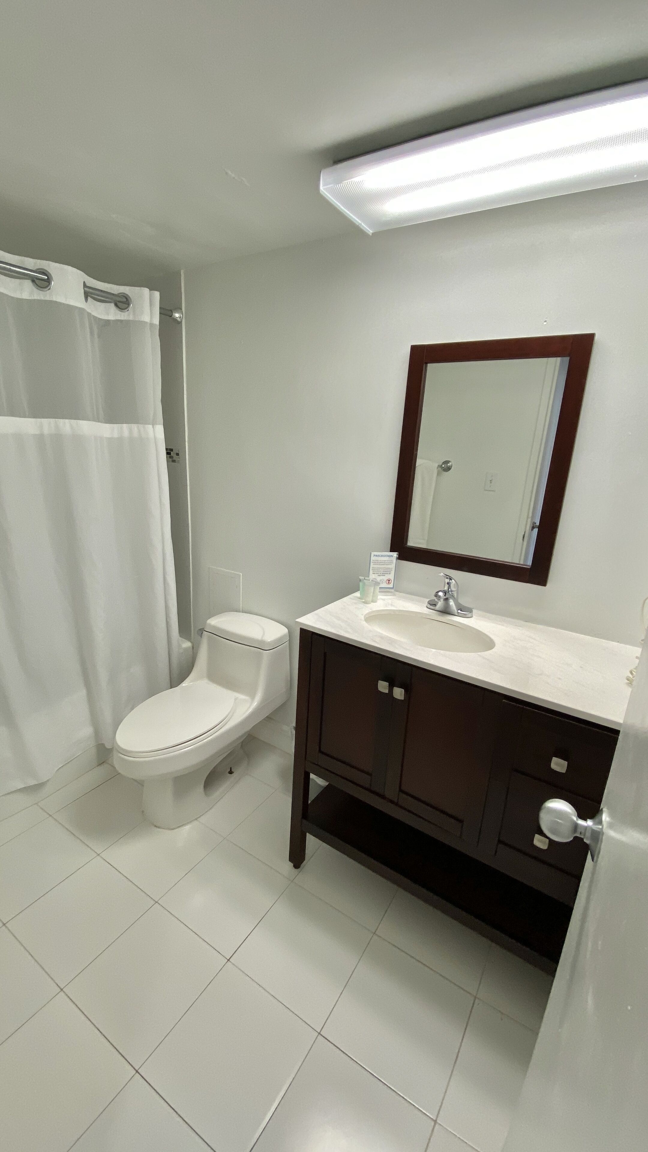 A bathroom with a toilet, sink, mirror, and shower curtain.