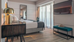 A modern hotel room with a bed, desk, chair, TV, and a bench. - Pestana Lisboa Vintage City Center Suites (Lisbon)