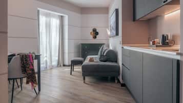A modern kitchen with grey cabinets, a dining area with a table and chairs, and a cozy seating area with a sofa and cushions.