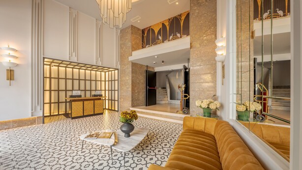 A modern lobby with a reception desk, patterned floor, and a large window with a view of the interior. - Pestana Lisboa Vintage City Center Suites (Lisbon)