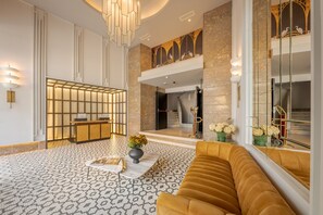 A modern lobby with a reception desk, patterned floor, and a large window with a view of the interior.